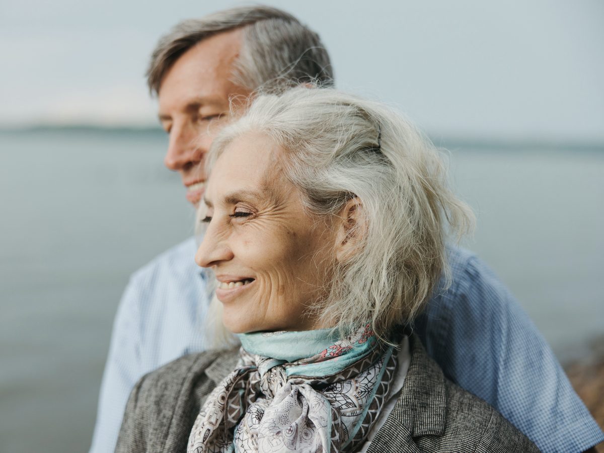 A smiling older woman with her partner close behind her