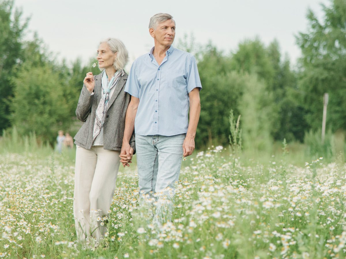 An older couple walking together through a flower field