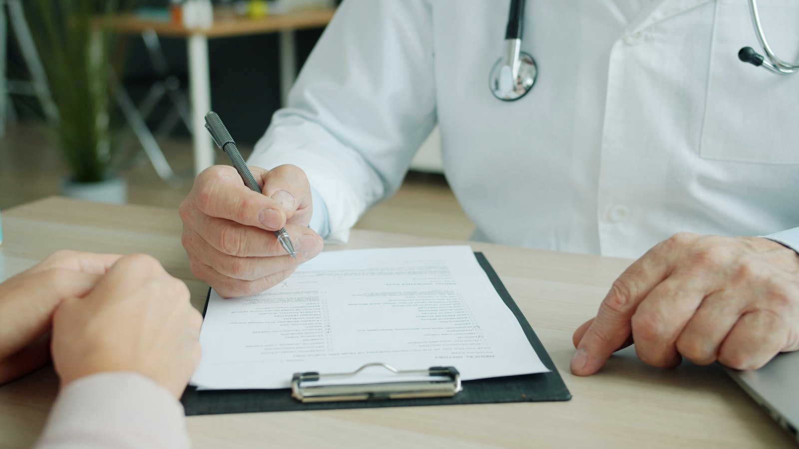 Hands and a clipboard during a consultation