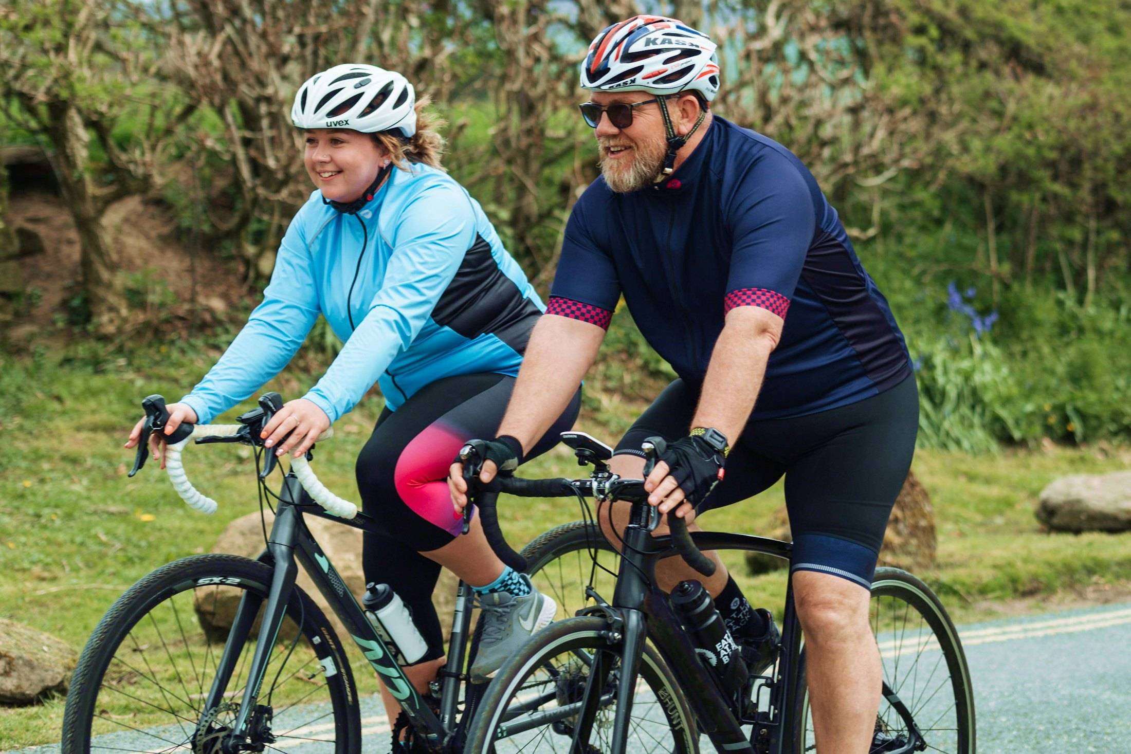 A couple in their fifties cycling together on a country road